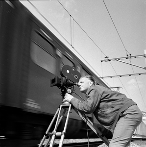 849527 Afbeelding van cineast Herman Wassenaar tijdens het filmen van treinen bij de spoorbrug over het ...